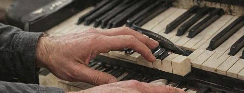 Piano technician tuning piano with professional tools